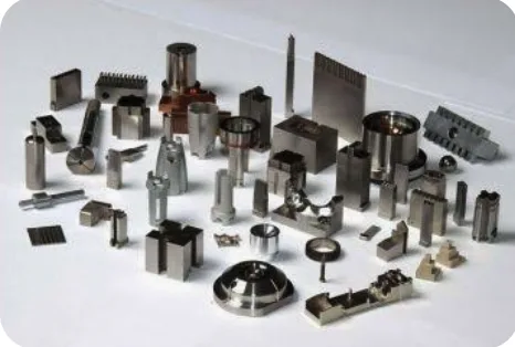 Milled and turned steel and brass parts laid out on a grey surface